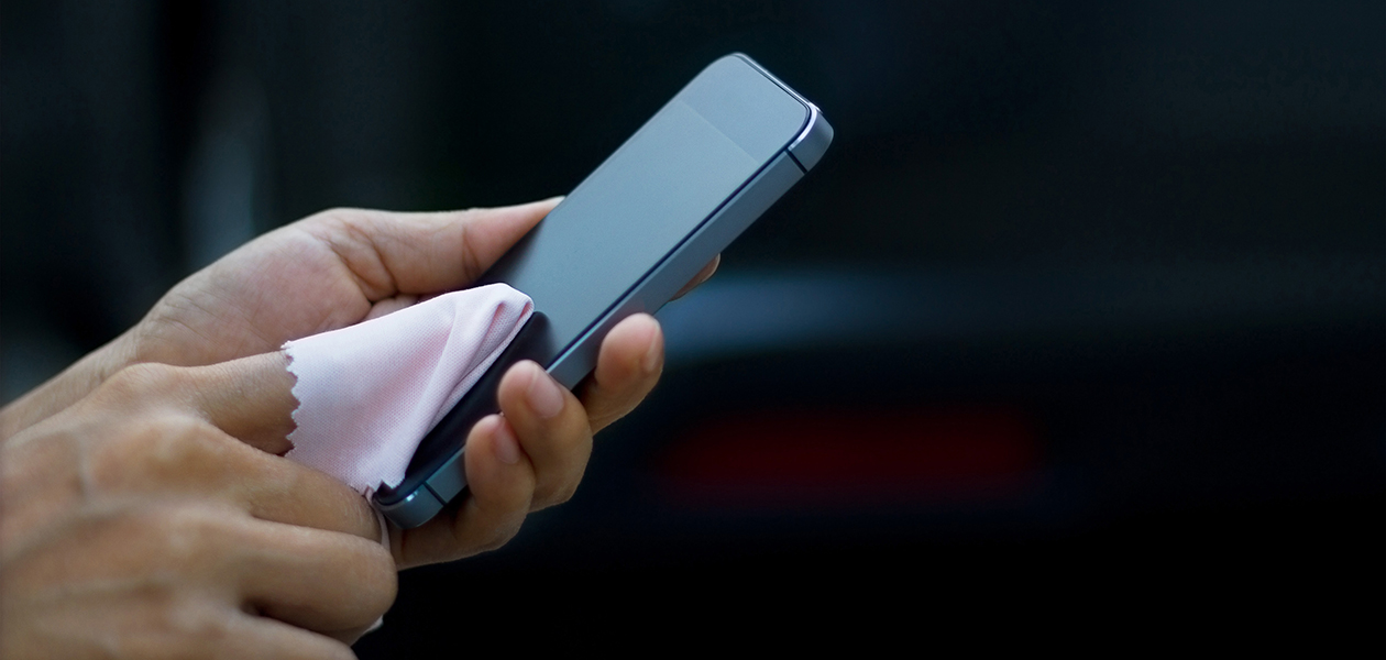 Husk at rense din mobiltelefon regelmæssigt Person rengør mobiltelefon