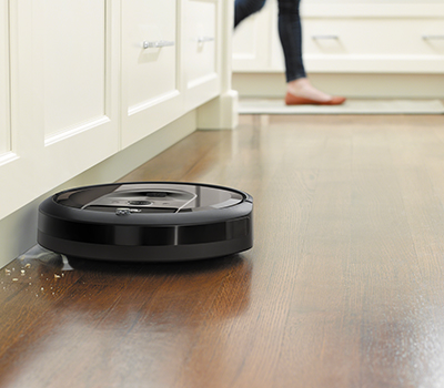 Robotdammsugare från iRobot som sugar upp brödsmulor Bild på roomba-dammsugare som suger upp smulor i ett kök
