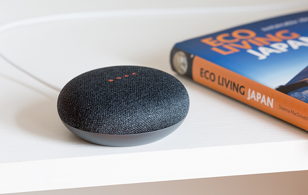 Der er talrige muligheder for at få finansrådgivning og rejsetips med Google Home Billede a fen Google Home mini højttaler ved siden af en bog