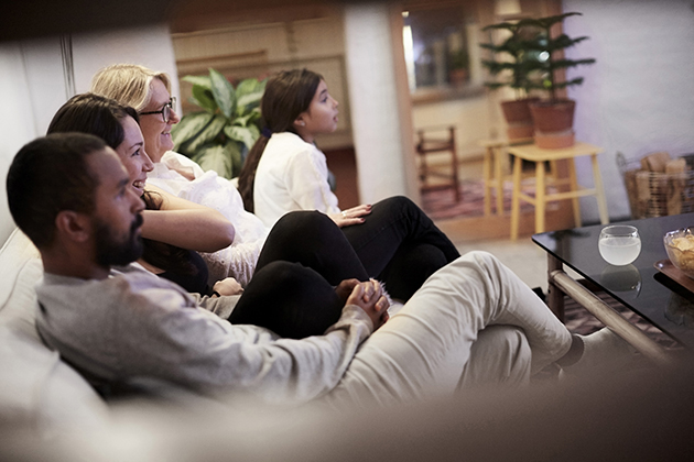 Skab stemning med smart belysning og underholdning En familie samlet i en sofa