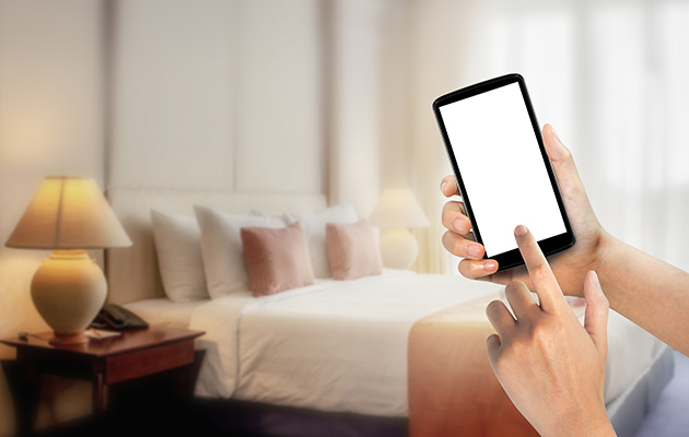 Hold fokus på at opgradere specifikke rum eller områder Billede af en smartphone i en hånd med et soveværelse i baggrunden
