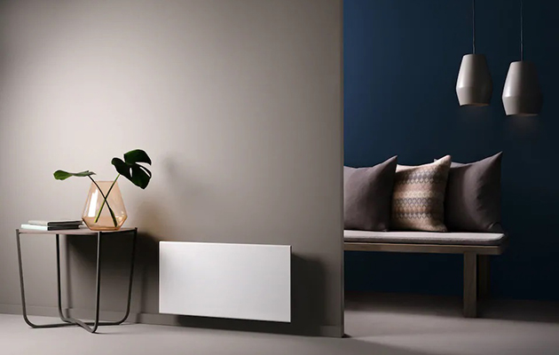 Du kan styre varmen derhjemme via mobilen En hvid el-radiator i et minimalistisk indrettet rum