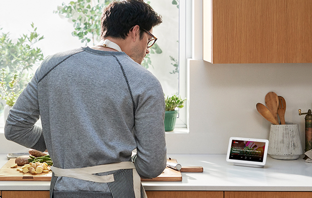 Afspil videoer og sange fra YouTube En mand ser YouTube på Google Home Hub og får hjælp til madlavning