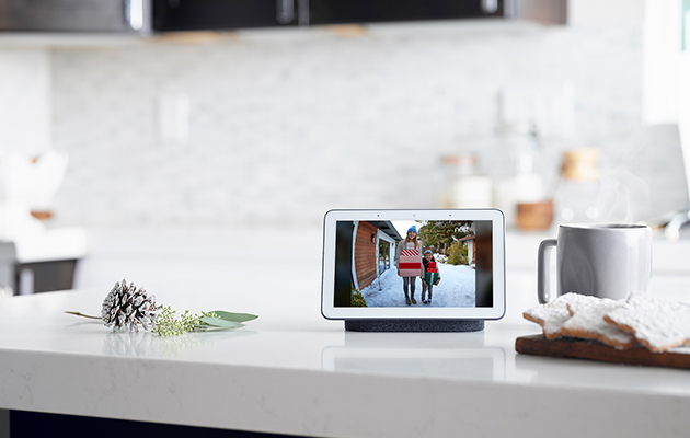 Se din kalender din, rejseinformation, påmindelser og andet med Voice Match. Google nest hub på køkkenbord med billeder fra kameraet udenfor