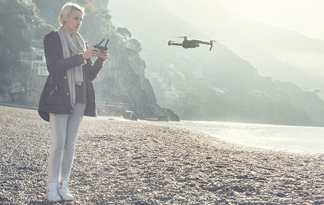Se verden fra en anden vinkel En dame som flyver med en drone over en strand