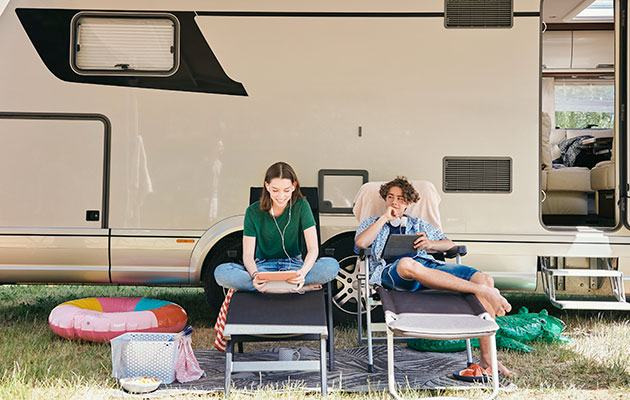 Sørg for at have underholdning med på ferie To unge mennesker foran autocamper