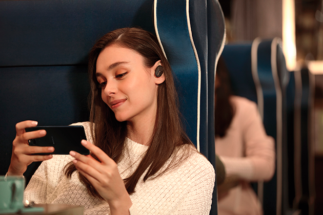 Sony WF-1000XM3 ægte trådløse støjreducerende hovedtelefoner Kvinde med Sony WF-1000XM3 ægte trådløse støjreducerende hovedtelefoner i et tog
