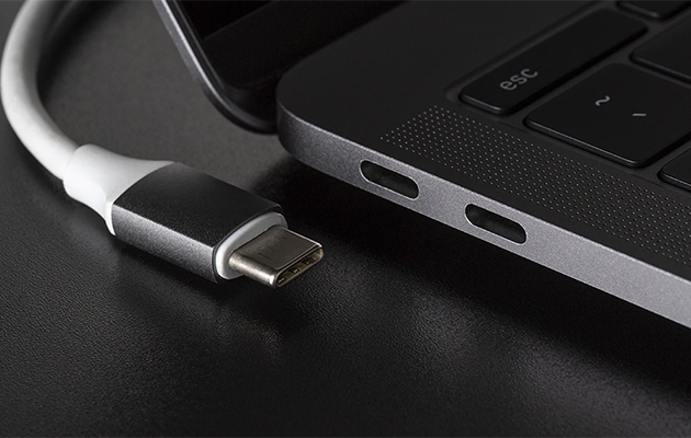 USB-C - Én port, mange muligheder Et USB-C stik ved siden af en laptop med to USB-C porte