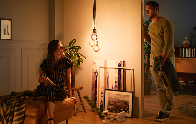 Energibesparende LED-pærer Philips LED Vintage hænger i et rum, hvor en mand og en kvinde taler sammen