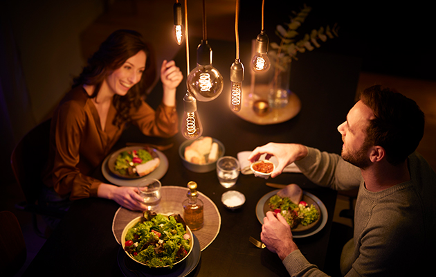 Philips LED Vintage skaber en hyggelig stemning derhjemme Philips LED Vintage hænger over spisebord, hvor en mand og en kvinde spiser middag