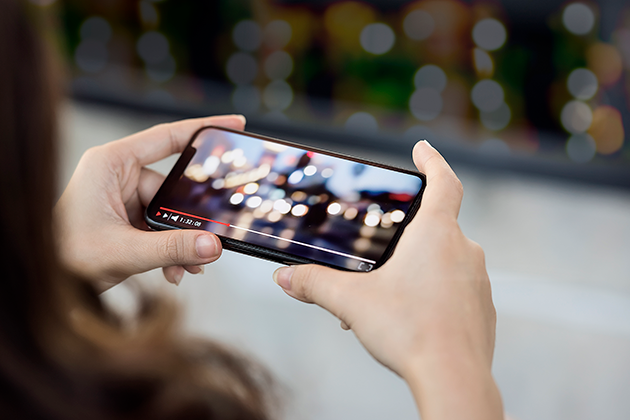 Se film og serier på farten Kvinde holder mobiltelefon, mens hun ser en video