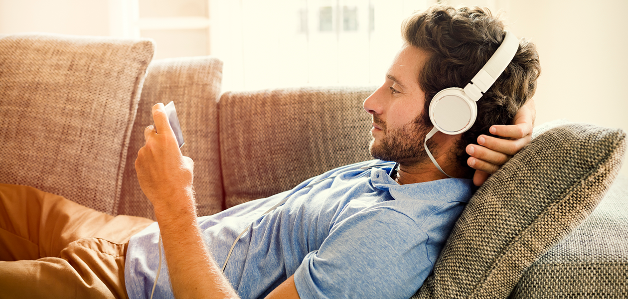 Find den bedste smartphone til at se film og serier på Mand ligger på sofa og ser på sin mobiltelefon