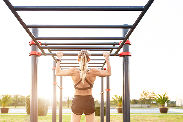Vælg et sportsur, der gør at du kan blive ved med at træne og ikke løber tør for batteri Kvinde tager en pull-up med et sportsur på håndleddet