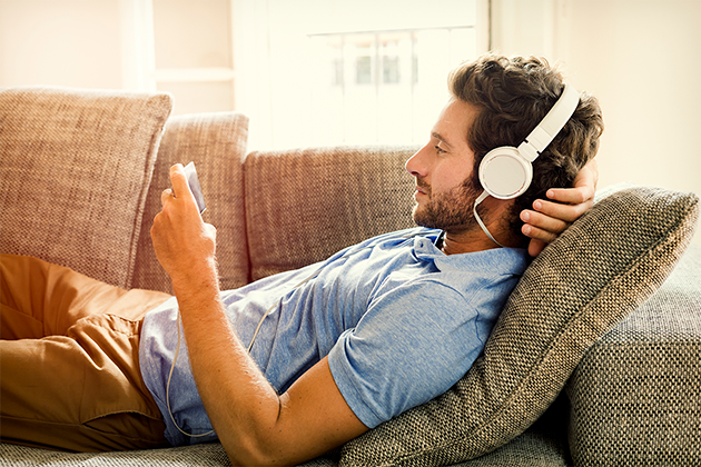 Med en smartphone i hånden kan du altid finde underholdning Mand ligger på sofa og ser på sin smartphone