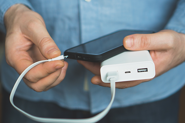 Du kan let lade din telefon op med en powerbank Person holder mobiltelefon og powerbank