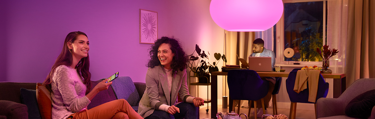 Philips Hue – Bridge vs Bluetooth Philips Hue-lampe i loftet over to kvinder, der sidder i en sofa