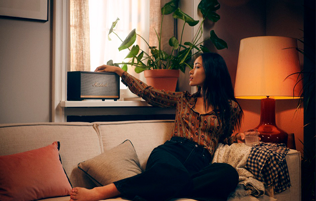 Bluetooth 5.0 har fire ganger så lang rækkevidde som Bluetooth 4.2 Kvinde på sofa tænder for højttaler