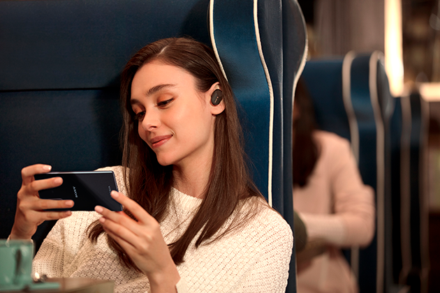 Sony Xperia 5 har Dolby Atmos lyd Kvinde sidder i toget med Sony Xperia 5 og høretelefoner