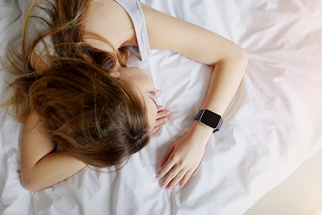 Hvordan måles din søvn? Kvinde sover med smartwatch på