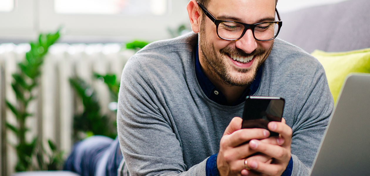 Vi gør det let at skifte telefon Smilende mand kigger på sin telefon