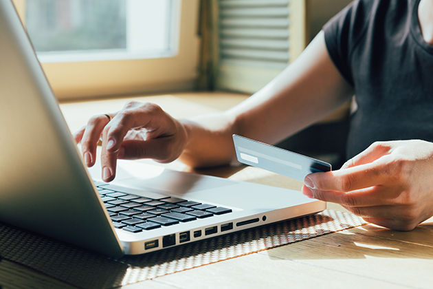 Prisen på en ny telefon er vigtig Person sidder foran computer med kreditkort i hånden