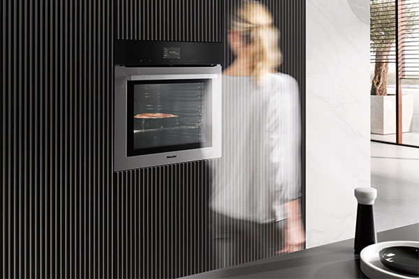 MotionReact – interagér med ovnen ved hjælp af dine bevægelser Miele ovn Generation 7000 med MotianReact passeres af kvinde