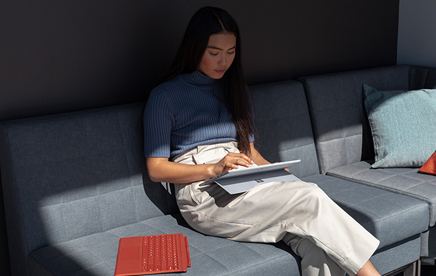 Brug Surface Pro 7 på din måde Kvinde som sidder i en sofa og bruger en Surface Pro 7