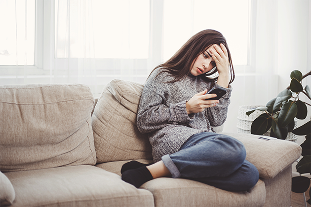 Smarte sikkerhedsregler til at beskytte din telefon Kvinde sidder på sofa og ser fortvivlet på sin telefon