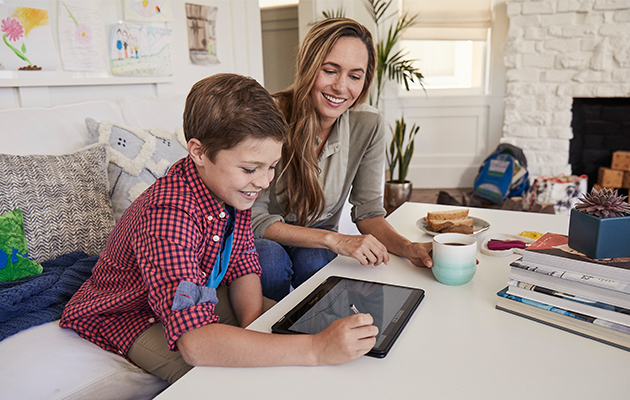 Del en Chromebook med hele familie Mor og søn sidder i sofaen og kigger på en Chromebook
