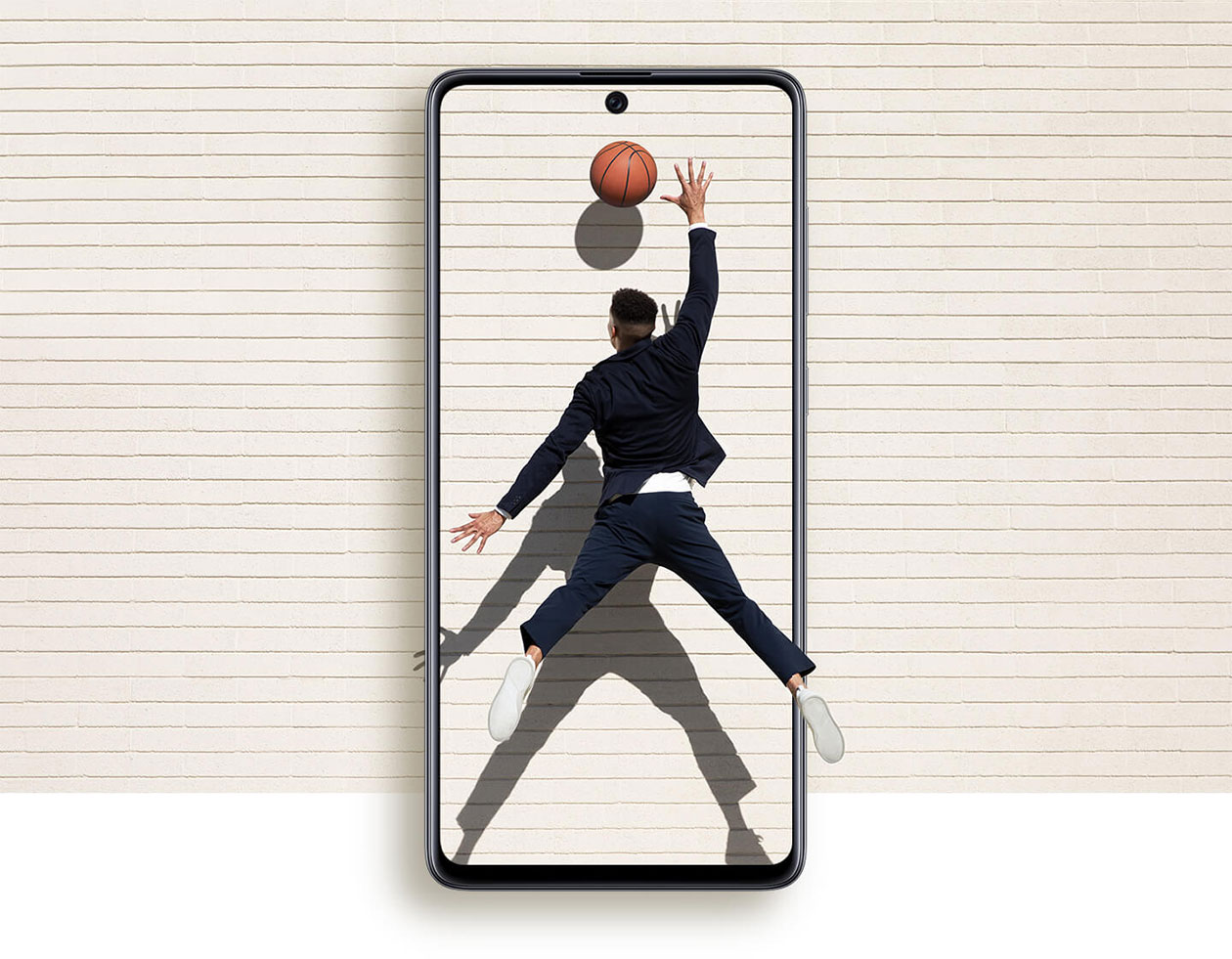 Oplev mere med en større skærm Forstørret Samsung Galaxy A71 mobiltelefon og mand, der rækker ud efter en basketball