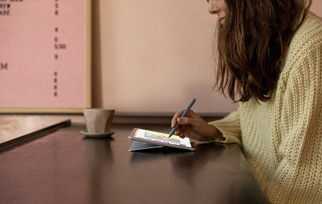 Surface Go 2 med 10,5 tommer stor skærm gør det let at følge med i det hele Kvinde sidder med Surface Pen i hånden og Surface Go 2