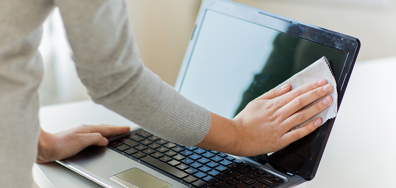 Tips til hvordan du rengør din laptop En hånd som rengør skærmen på en bærbar computer
