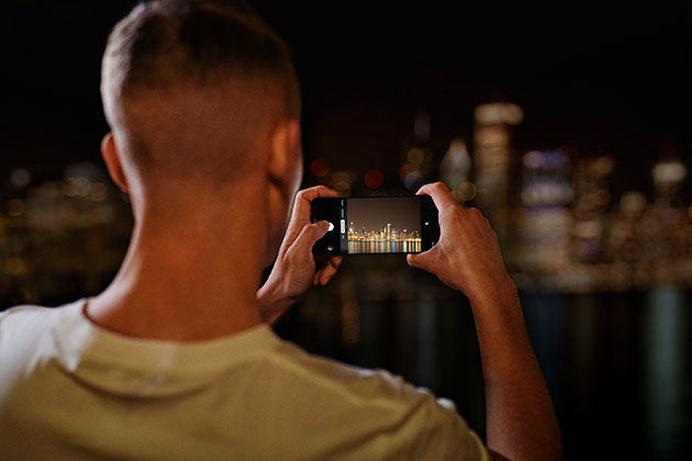 Opfang livets øjeblikke på billeder og videoer takket være et nyt 48 MP Quad-kamera OnePlus Nord anvendes af mand til at tage billede af en skyline om aftenen