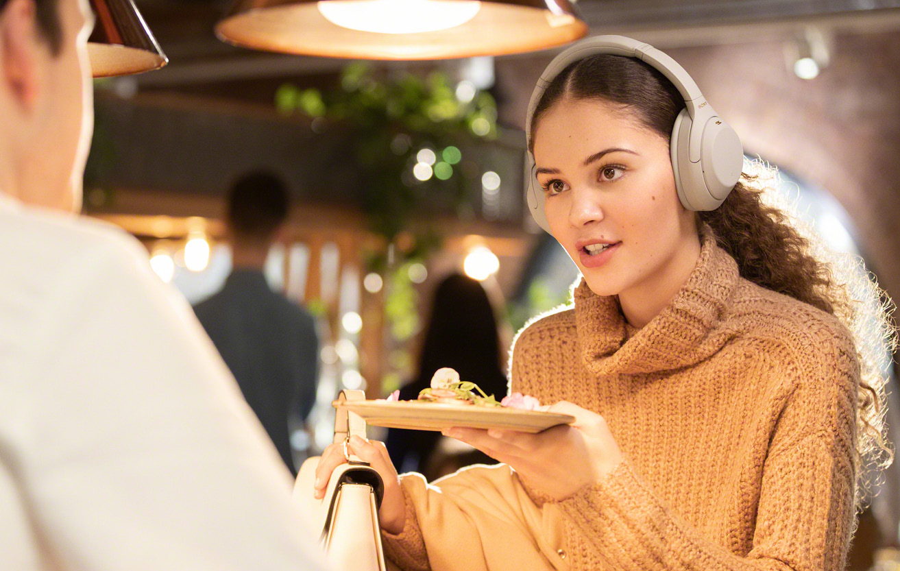 Wearing Detection pauser musikken eller slukker for hovedtelefonerne, når du tager dem af Kvinde spiser med hovedtelefoner på
