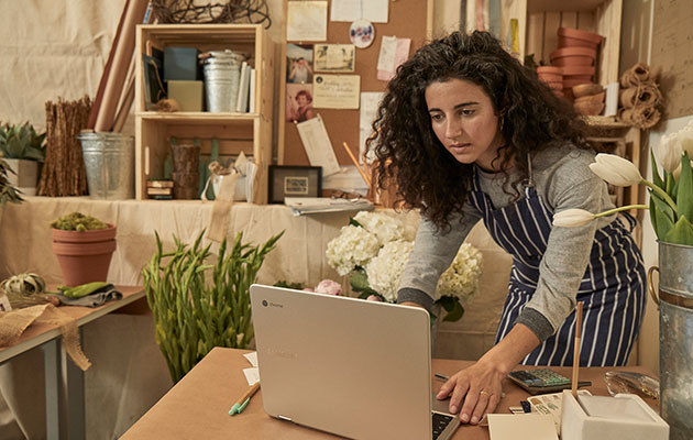 En Chromebook er klar når du er det Kvinde som står bøjet over et bord og anvender en Chromebook
