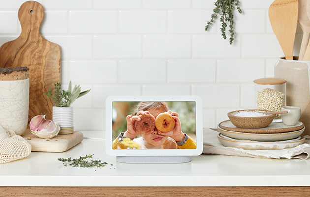 Skærmen viser automatisk dine bedste billeder fra Google Foto, så du altid har dine favoritter i baggrunden Pige med donuts foran øjnene på en Google Nest Hub-skærm