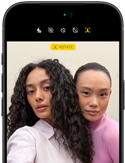 Sort iPhone 18 Pro vist forfra, mens det viser to modeller, der poserer foran kameraet for at demonstrere Center Stage-kameraet på forsiden