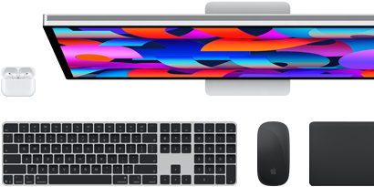 En samling af tilbehør og enheder, der blandt andet omfatter AirPods, Magic Keyboard med Touch ID, Magic Mouse, Magic Trackpad og Studio Display