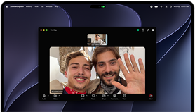 Sølvfarvet MacBook Pro med PROLED XDR-skærm, skærmen viser et igangværende videoopkald med en solbeskinnet by, hvor to personer vinker til en person derhjemme