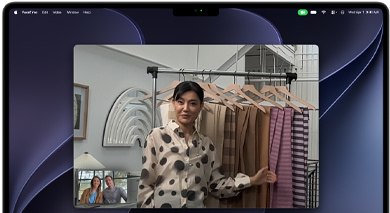 Et videoopkald på en MacBook Pro, hvor en kvinde viser stofprøver til to personer på opkaldet. Centreringsfunktionen holder hende i midten af billedet, når hun går rundt