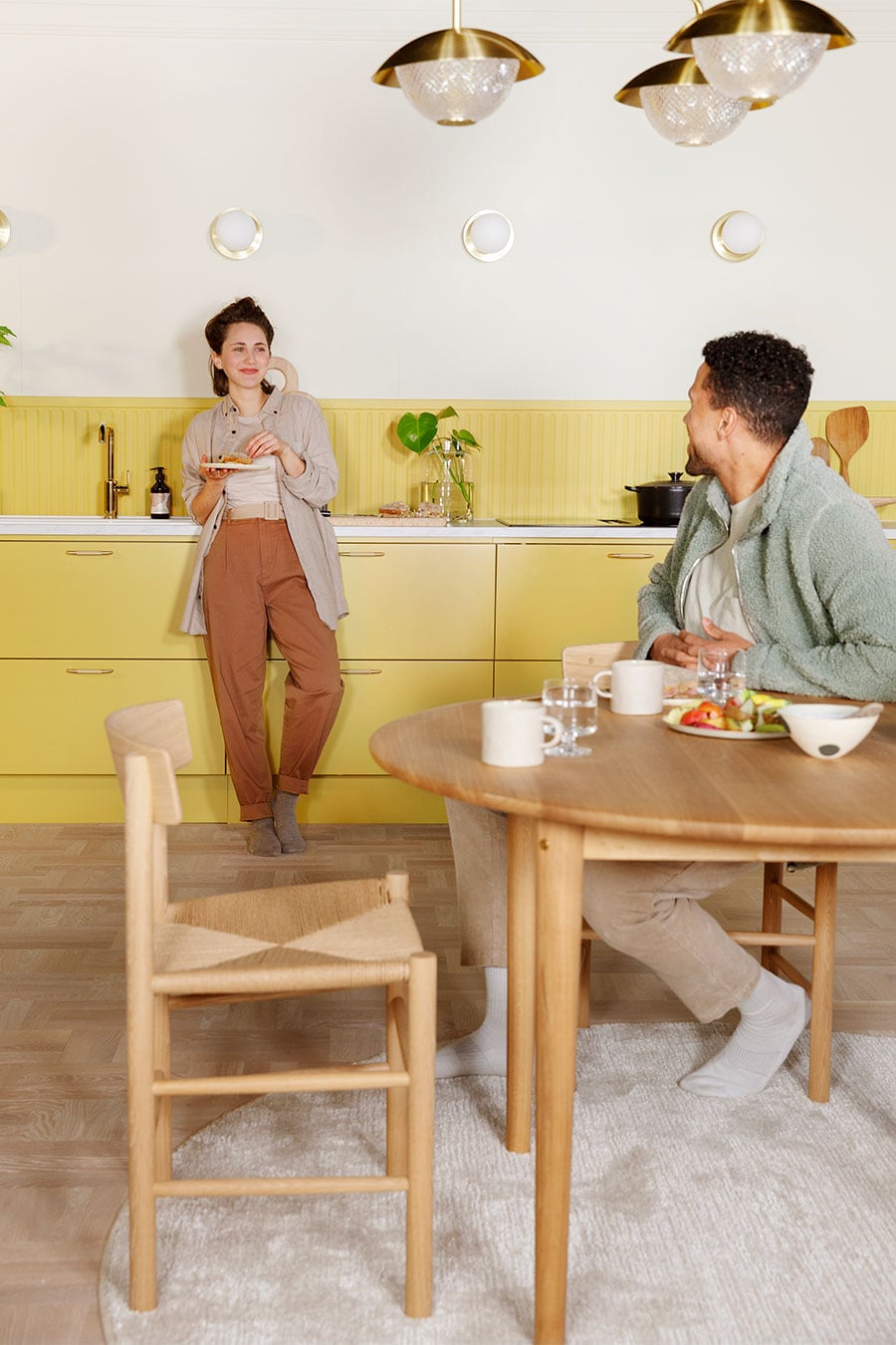 Gult EPOQ Trend-køkken med mand der sidder ved et bord og kvinde der står ved vasken