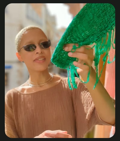 En dame der står og kigger på et meget grønt tørklæde på et udendørs marked