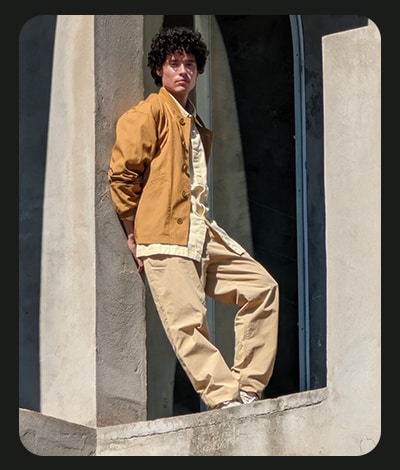 En ung mand står og læner sig op af en betonvæg udenfor