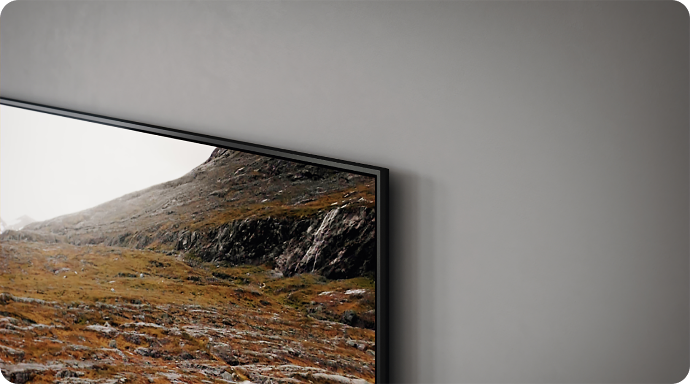 Nærbillede af et Samsung Q60C TV-hjørne på en grå væg