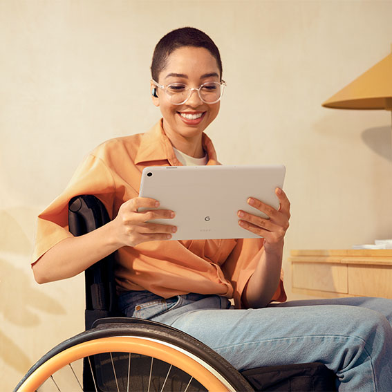 Kvinde i kørestol bruger Google Pixel Tablet i sit hjem