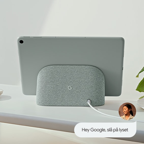 Pixel-tablet i opladningshøjttalerdock og en kvinde, der siger Hey Google, tænd lyset