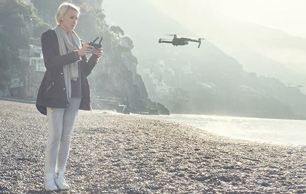 Kvinde flyver med drone nær en kyst