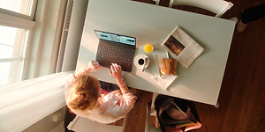 Kvinde der skriver på HP computer mens hun spiser frokost