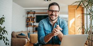 Smilende mand sidder ved sin bærbar computer