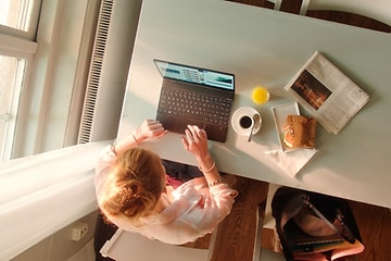 Kvinde der skriver på HP computer mens hun spiser frokost